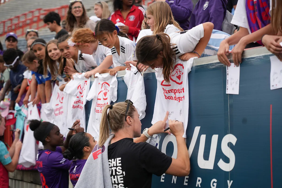 Wild FC players signing autographs for fans in the stands
