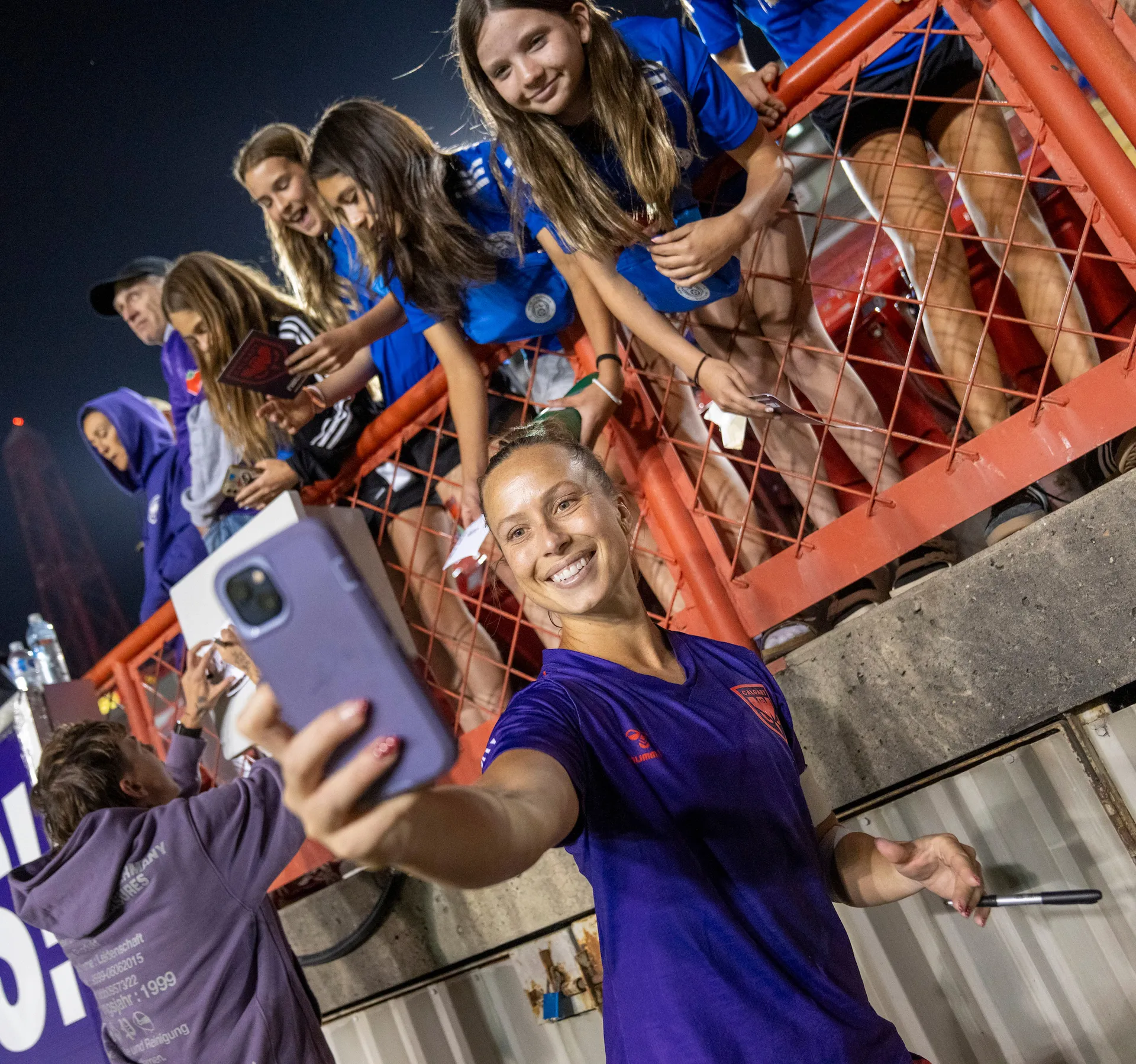 Calgary Wild FC player taking a selfie with a fan in the stands